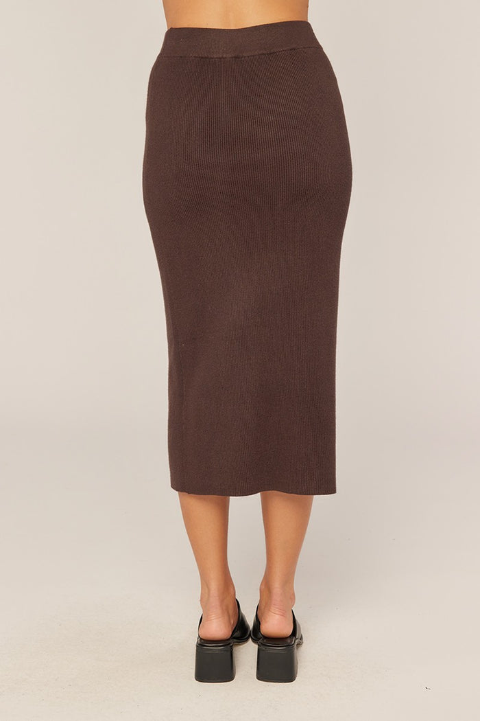 woman wearing a brown ribbed midi skirt, viewed from the back, with a fitted silhouette and high waist