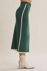woman wearing a dark green midi skirt with contrasting white side stripes and paired with ankle boots