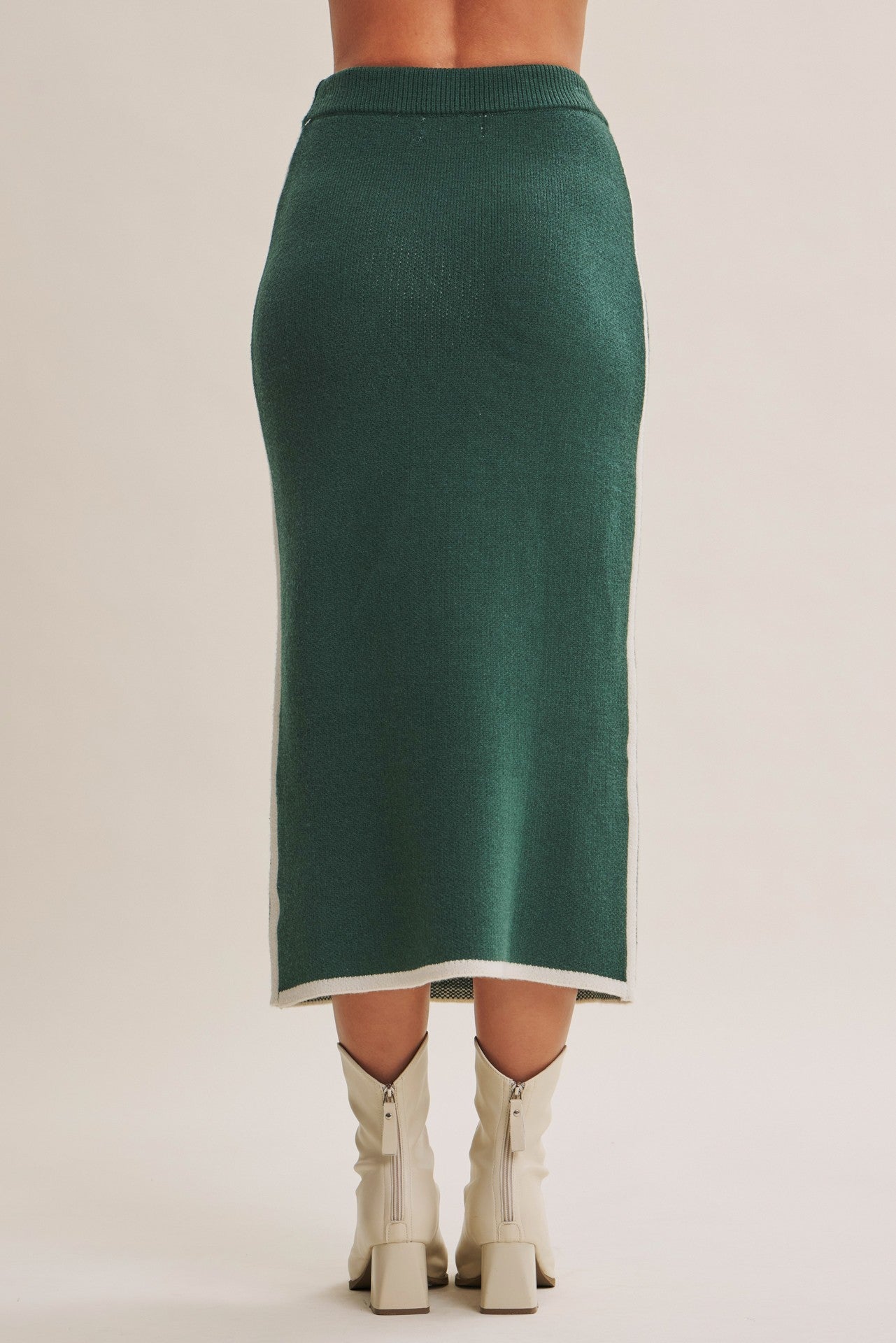 woman wearing a dark green knitted midi skirt with white side detailing and matching heeled boots