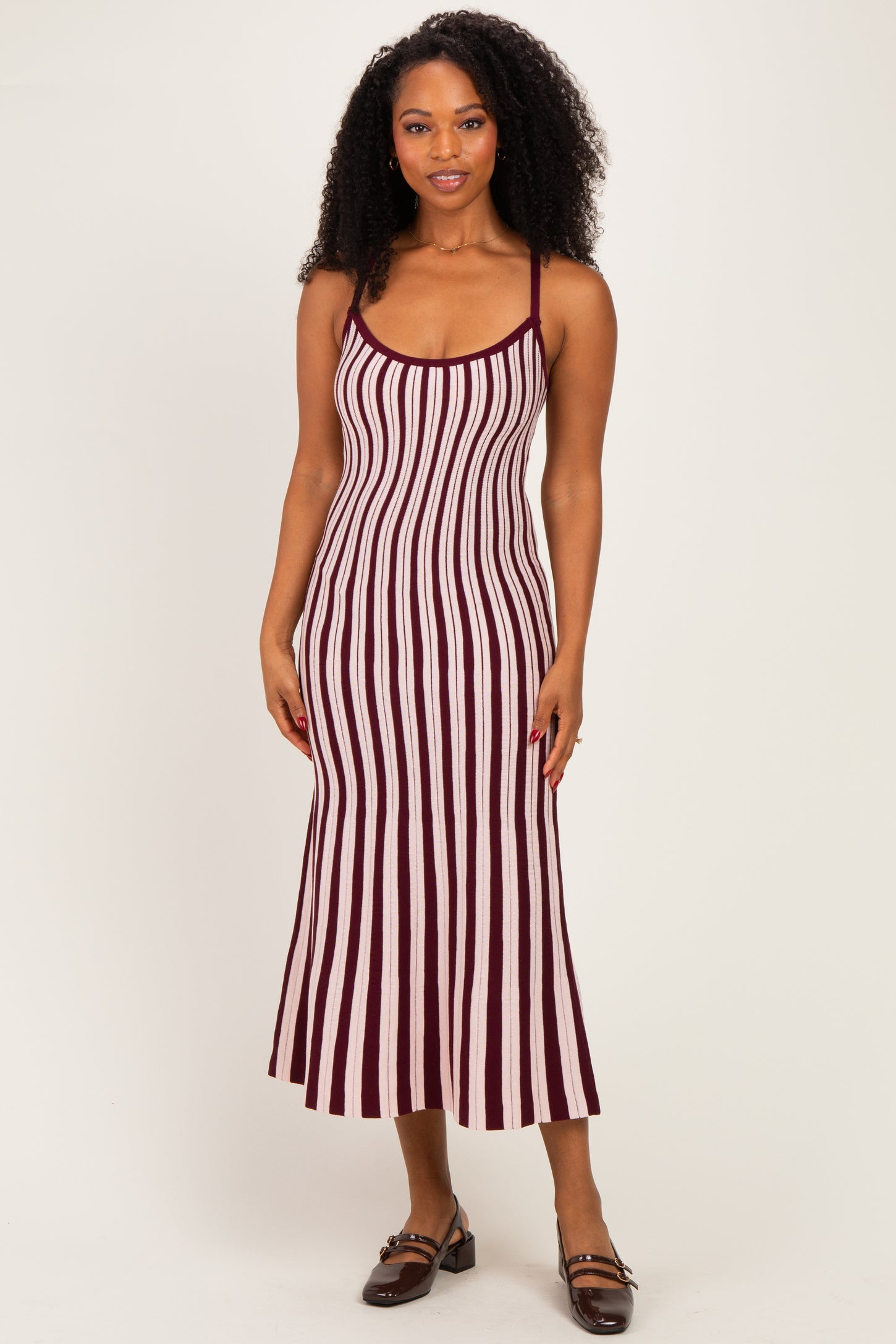 woman wearing a maroon and white striped midi dress with spaghetti straps and a fitted silhouette