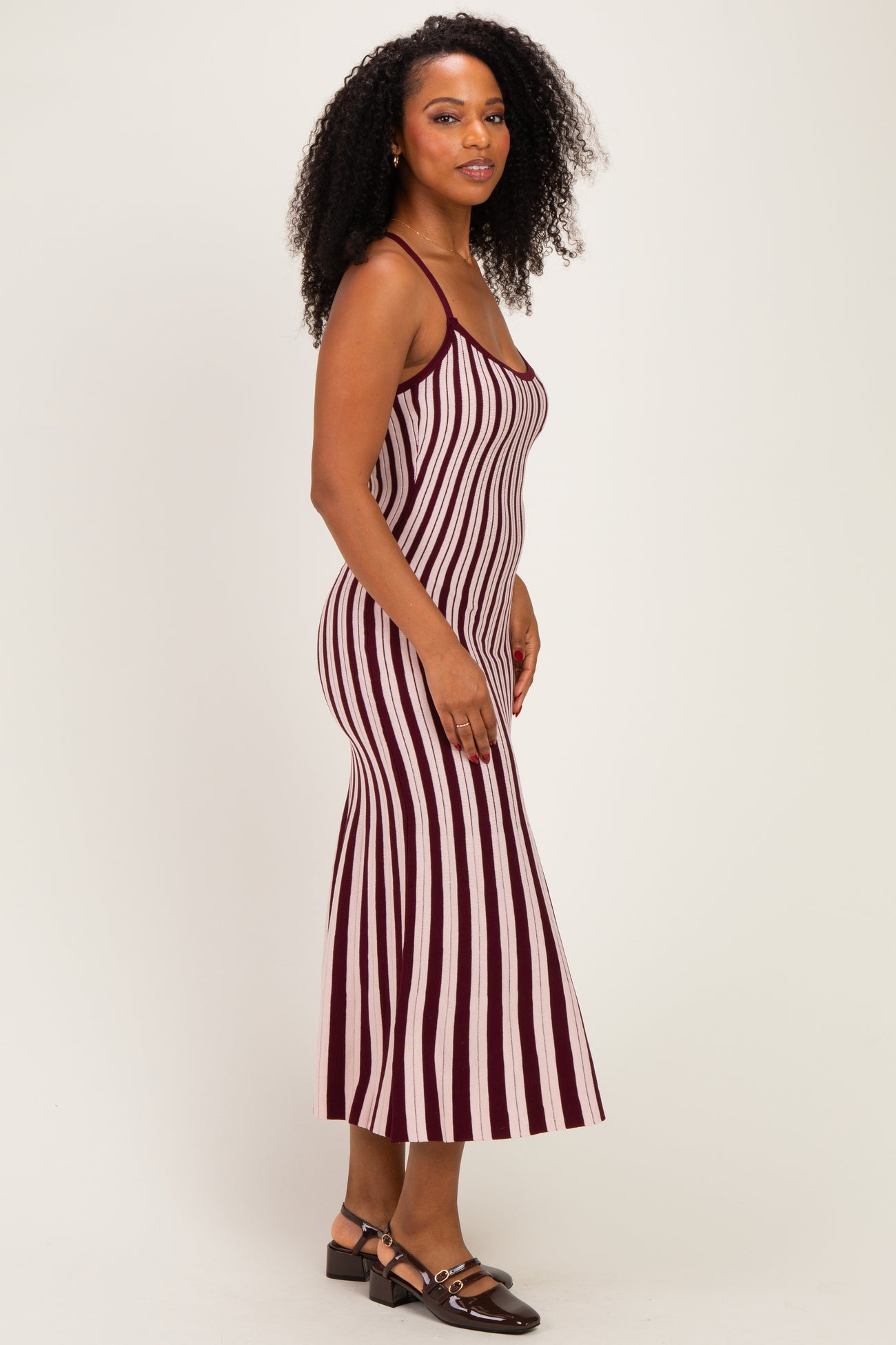 woman wearing a burgundy and white striped midi dress with spaghetti straps and a figure-hugging silhouette