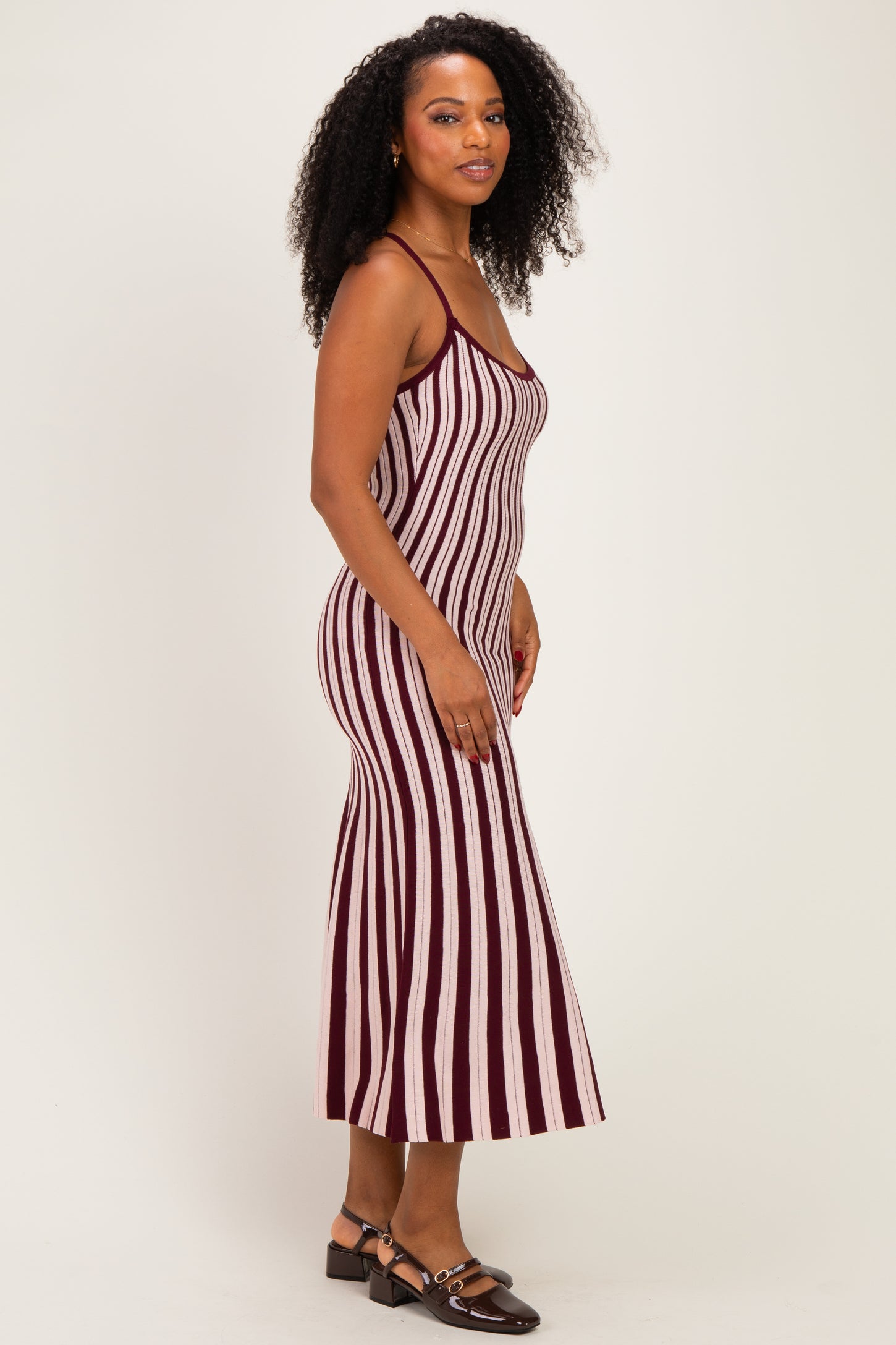 woman wearing a burgundy and white striped midi dress with spaghetti straps and a figure-hugging silhouette