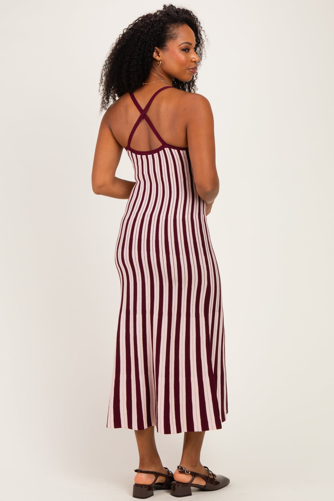 woman wearing a burgundy and white striped midi dress with crisscross straps at the back