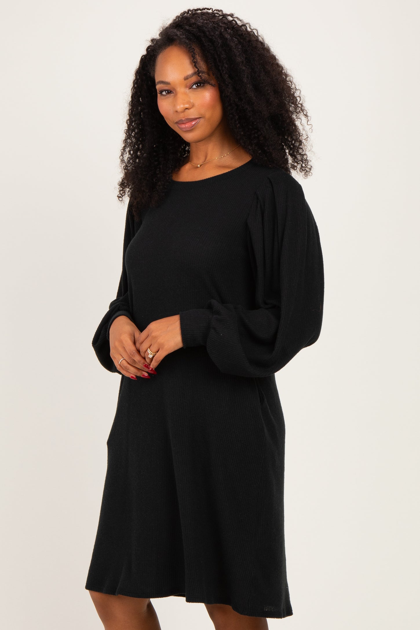 woman wearing a black ribbed long sleeve sweater dress with balloon sleeves and pockets