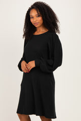 woman wearing a black ribbed long sleeve sweater dress with balloon sleeves and pockets