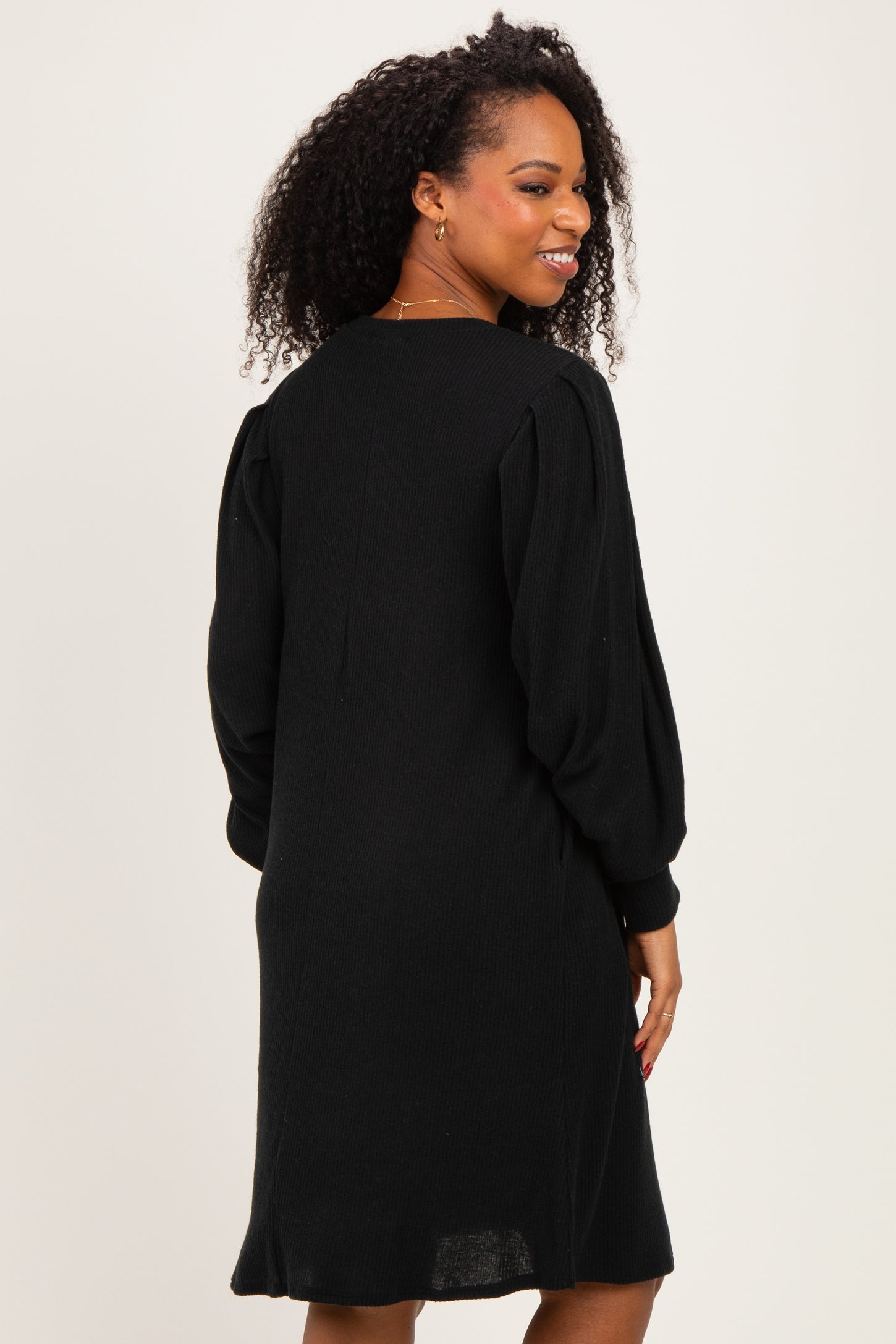 woman wearing a black knitted dress with long sleeves and a relaxed fit, showing the back view