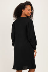 woman wearing a black knitted dress with long sleeves and a relaxed fit, showing the back view