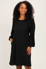 woman wearing a black long sleeve knit dress with puffed sleeves and a relaxed fit