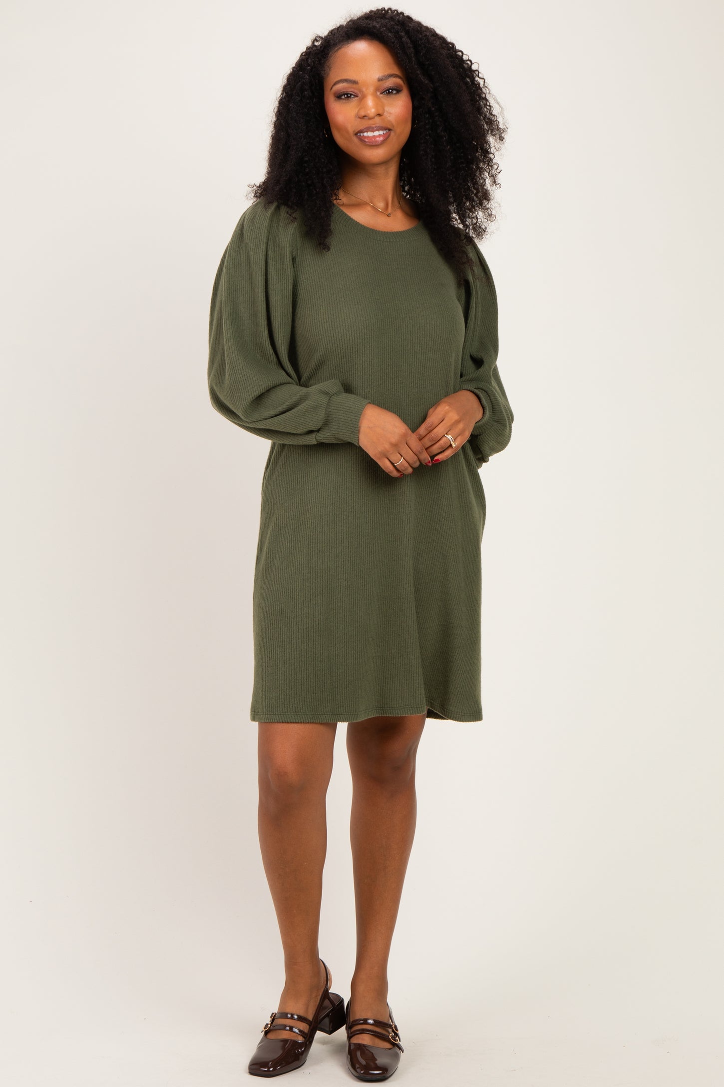 woman wearing an olive green sweater dress with puff sleeves and a relaxed fit
