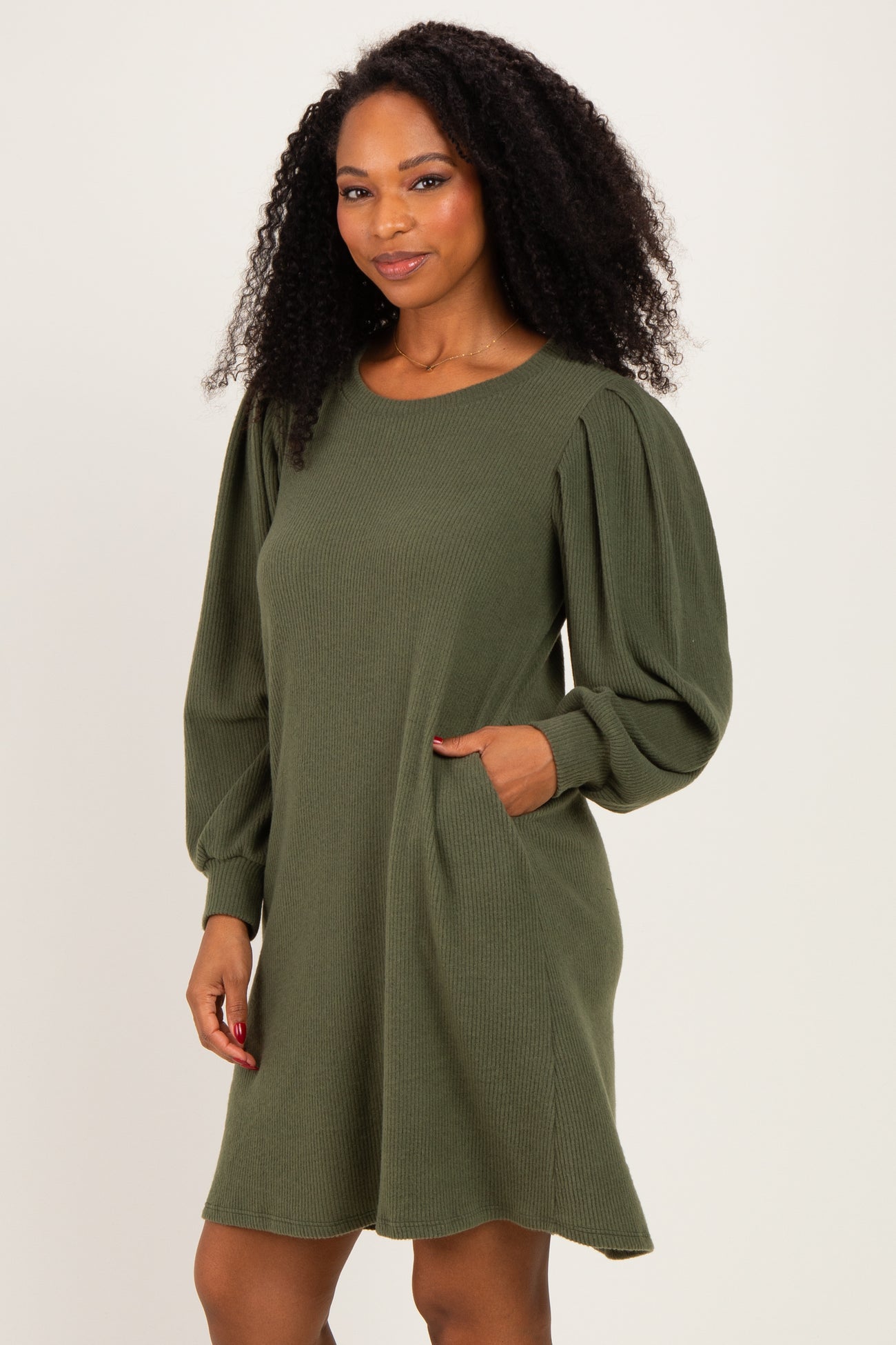 woman wearing an olive green ribbed long sleeve dress with puffed sleeves and side pockets
