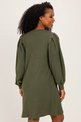 woman wearing a dark green long sleeve sweater dress with puffed sleeves and a relaxed fit