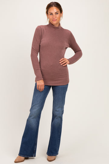 woman wearing a mauve ribbed long sleeve turtleneck sweater paired with flared jeans and beige heels