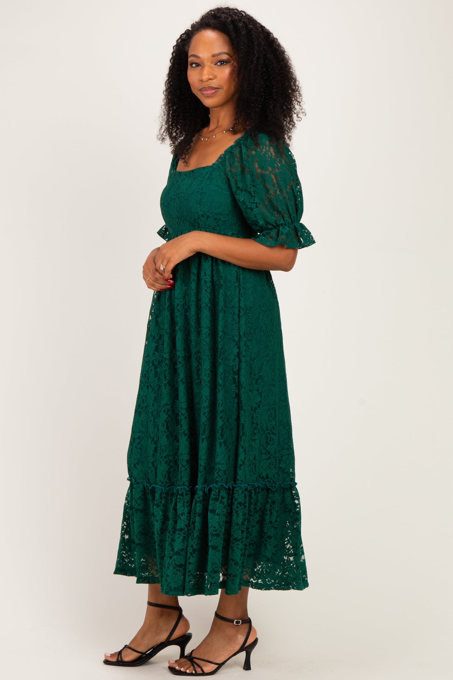 woman wearing a green lace maxi dress with short puff sleeves and a tiered hemline