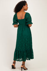 woman wearing a green lace midi dress with a smocked bodice and puff sleeves, showing a ruffled hem and open back