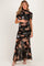 woman wearing a black floral maternity gown with short sleeves and a fitted bodice, holding her baby bump