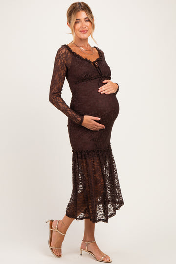 woman wearing a dark brown lace maternity dress, showcasing her baby bump, standing with one hand on her belly