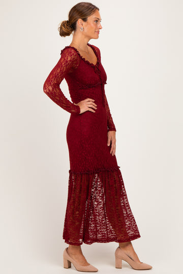 woman wearing a burgundy lace long sleeve maxi dress with a ruffled hem and a fitted silhouette