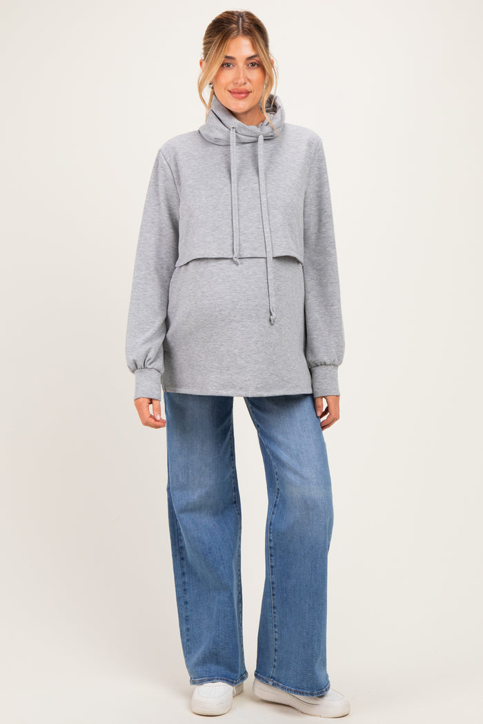woman wearing a gray cropped maternity hoodie with a drawstring and paired with wide-leg jeans, showing a baby bump