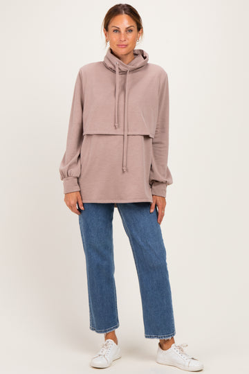 woman wearing a mauve oversized hoodie with a cropped layer and long sleeves paired with blue straight-leg jeans