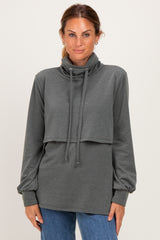 woman wearing a dark gray long sleeve cowl neck sweatshirt with a layered design and drawstring details