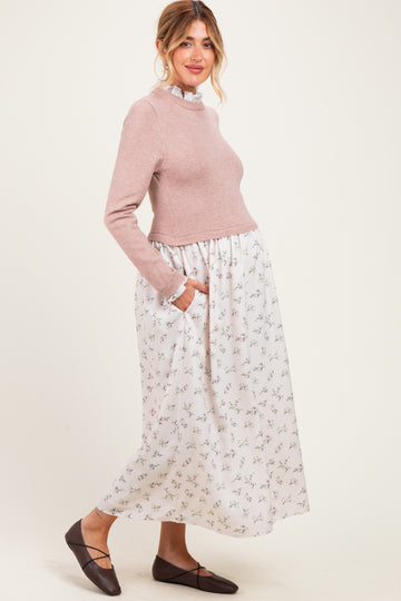 woman wearing a pink long sleeve maternity sweater and a floral print maxi skirt with pockets, showing her baby bump