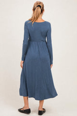 woman wearing a long sleeve blue maternity dress with a flowing skirt, showcasing a relaxed fit and gathered waist detail