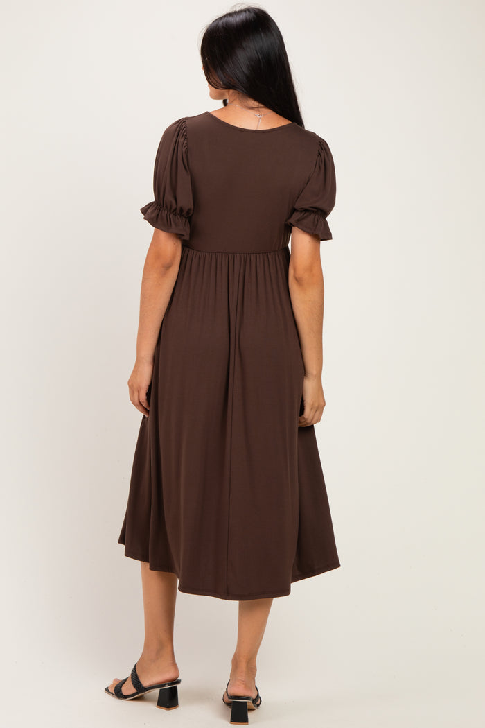 woman wearing a brown midi dress with puff sleeves and a fitted waist, seen from the back