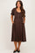 woman wearing a brown puff sleeve maternity dress with buttons and pockets, showcasing her baby bump
