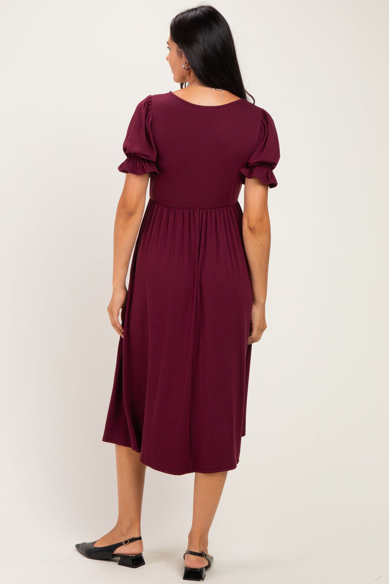 woman wearing a burgundy midi dress with puff sleeves and a fitted waist, viewed from the back