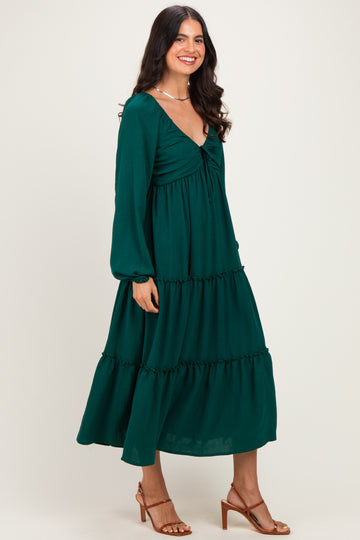 woman wearing a dark green tiered maxi dress with long sleeves and a v-neckline, standing sideways