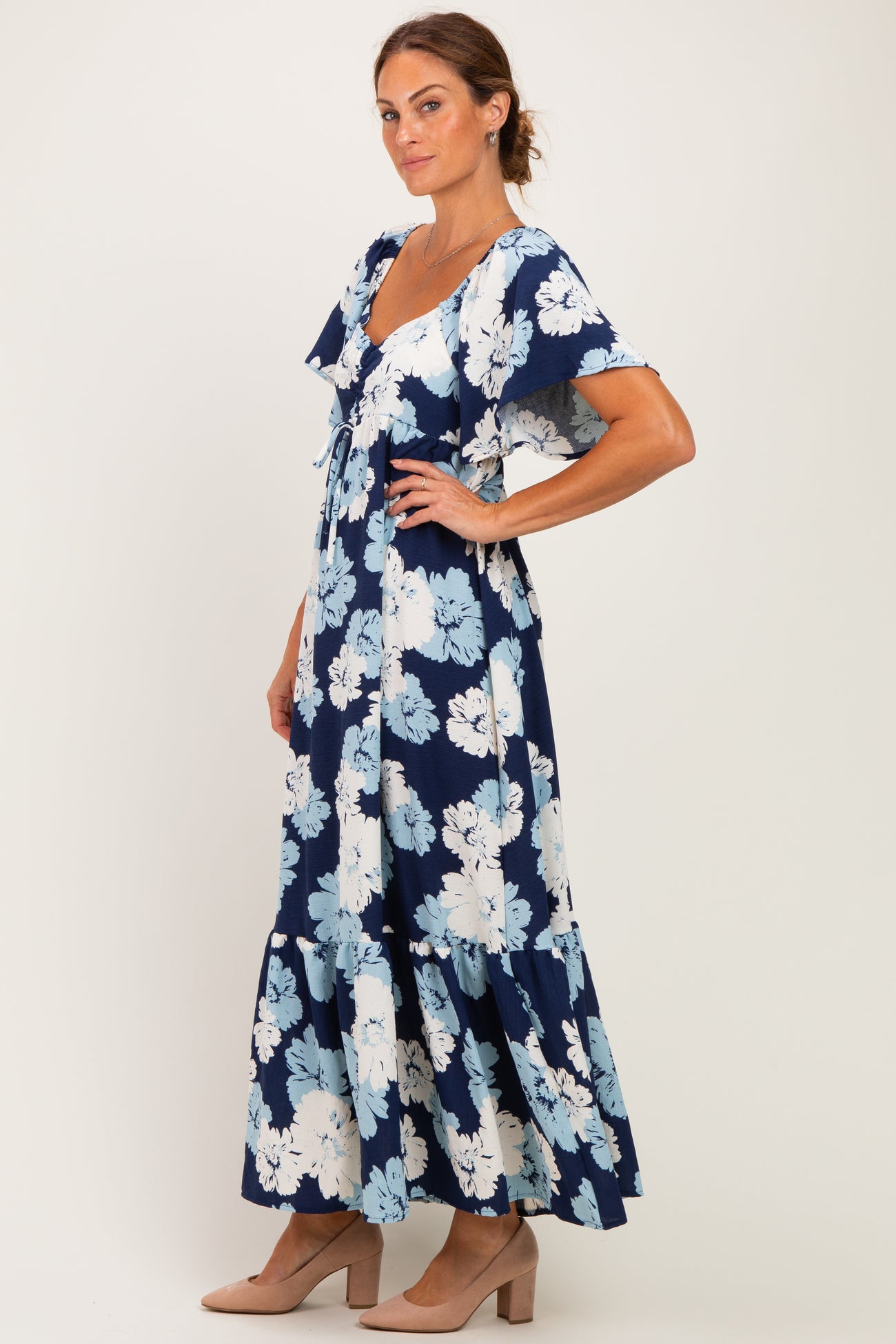 woman wearing a navy blue floral maxi dress with ruffled sleeves and a tiered skirt, posing sideways