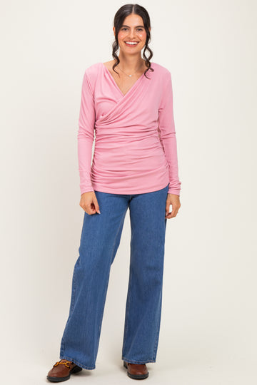 woman wearing a pink long sleeve wrap top paired with blue wide-leg jeans
