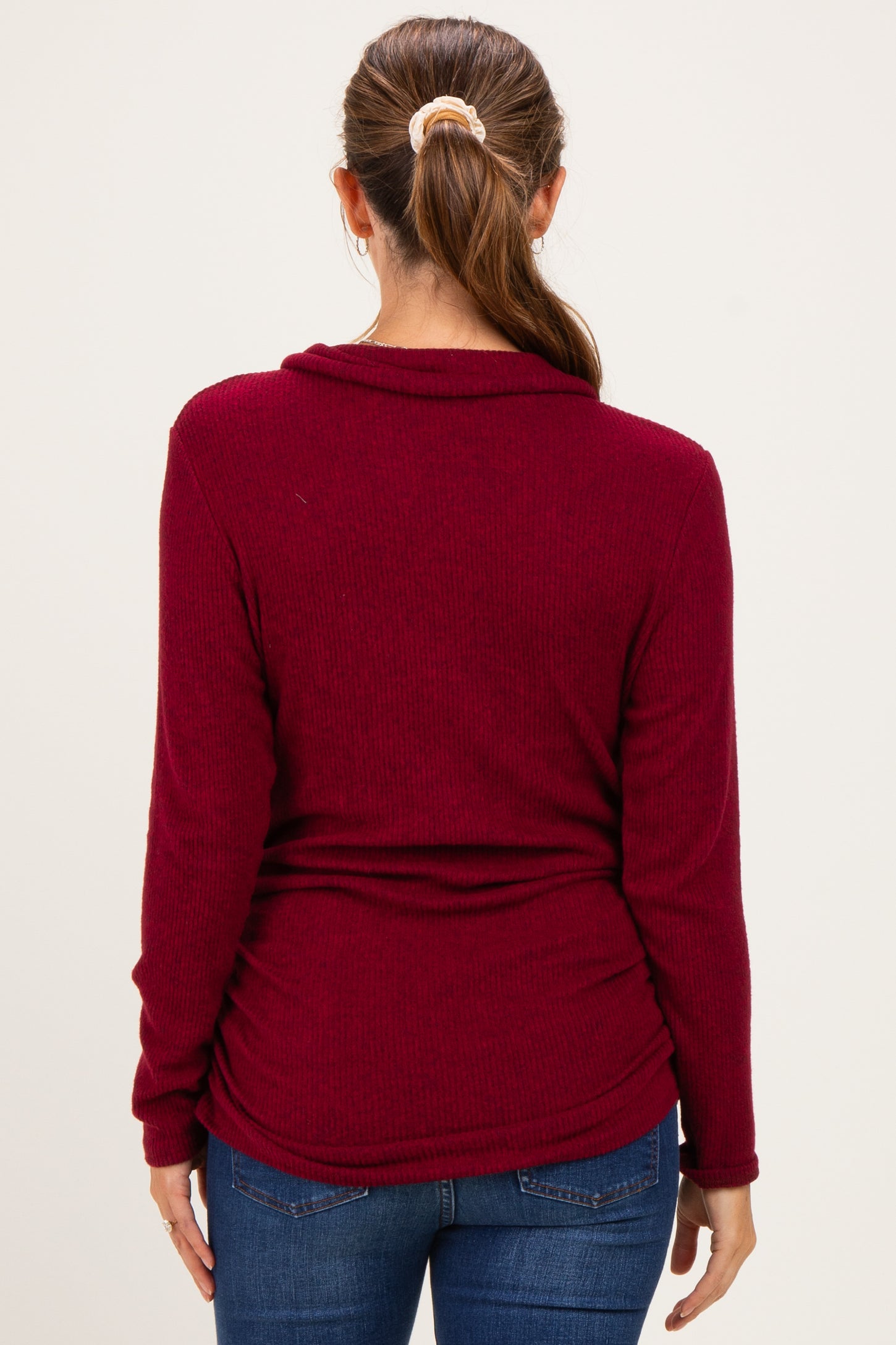 woman wearing a burgundy maternity top with a cowl neck and gathered sides, showing a relaxed fit from the back