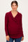 woman wearing a burgundy long sleeve maternity top with a crossover design and ruched sides, showing a baby bump