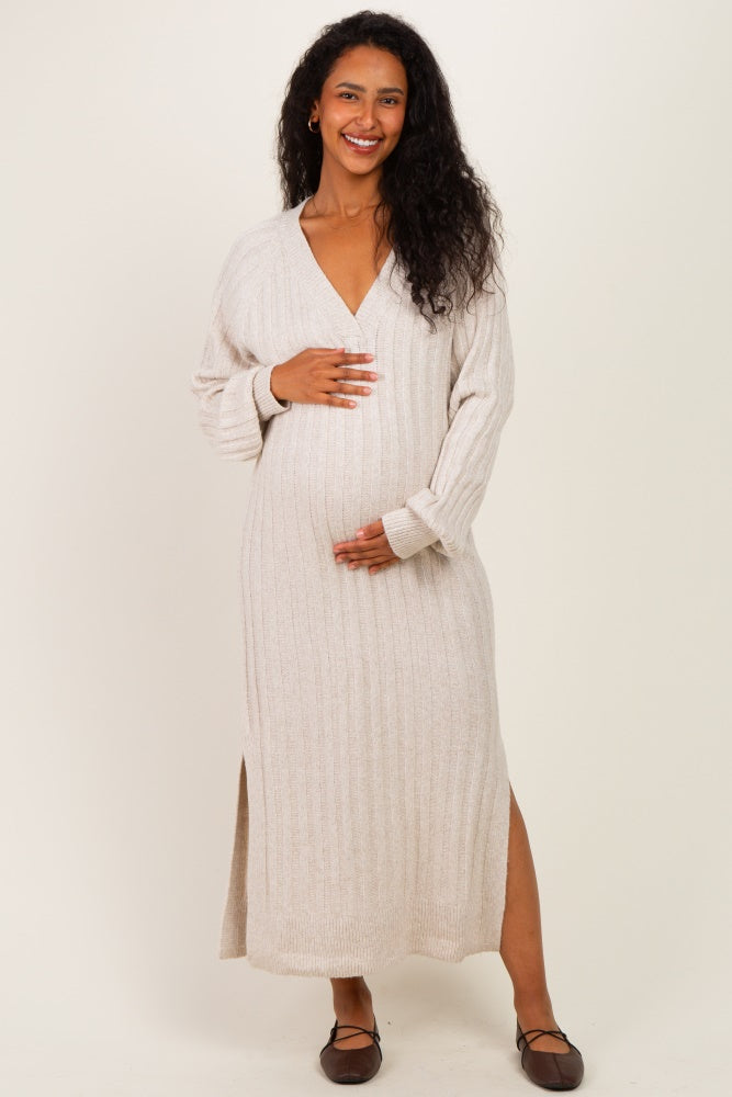 woman wearing a beige ribbed long sleeve maternity dress, standing and holding her baby bump