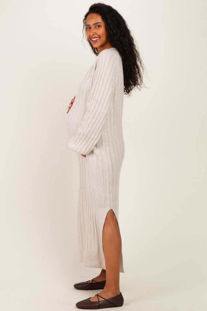woman wearing a cream ribbed maternity maxi dress with side slits and holding her baby bump
