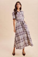 woman wearing a purple and white plaid button-up maxi dress with short sleeves and a tied waist