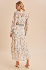 woman wearing a floral long sleeve maxi dress with a cinched waist, standing against a neutral background