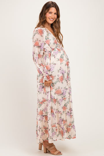 woman wearing a flowy floral maternity maxi dress with a v-neckline and ruffled hem, showing her baby bump