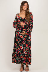 woman wearing a black floral maternity maxi dress with long sleeves and a baby bump visible