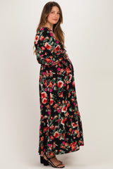 woman wearing a black floral maternity maxi dress with long sleeves and a flowy hem, showcasing her baby bump