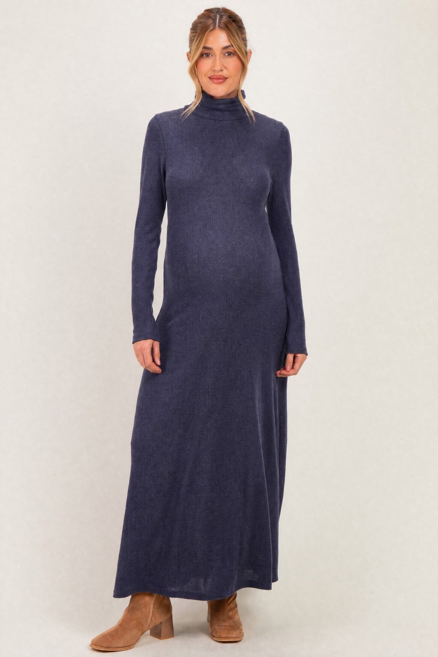 woman wearing a dark blue long sleeve ribbed maternity dress with a fitted silhouette and a visible baby bump