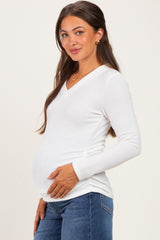 woman wearing a white long sleeve maternity top and showing her baby bump