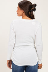 woman wearing a white long sleeve maternity top from the back, styled with a slight curve at the hem