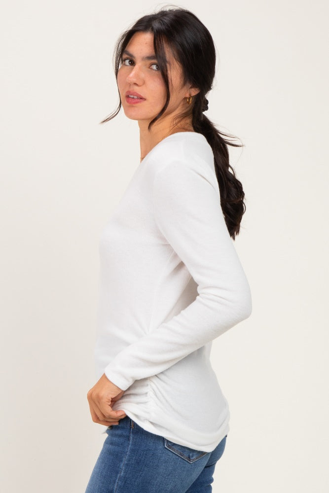 woman wearing a white long sleeve top with side ruching and styled with blue jeans