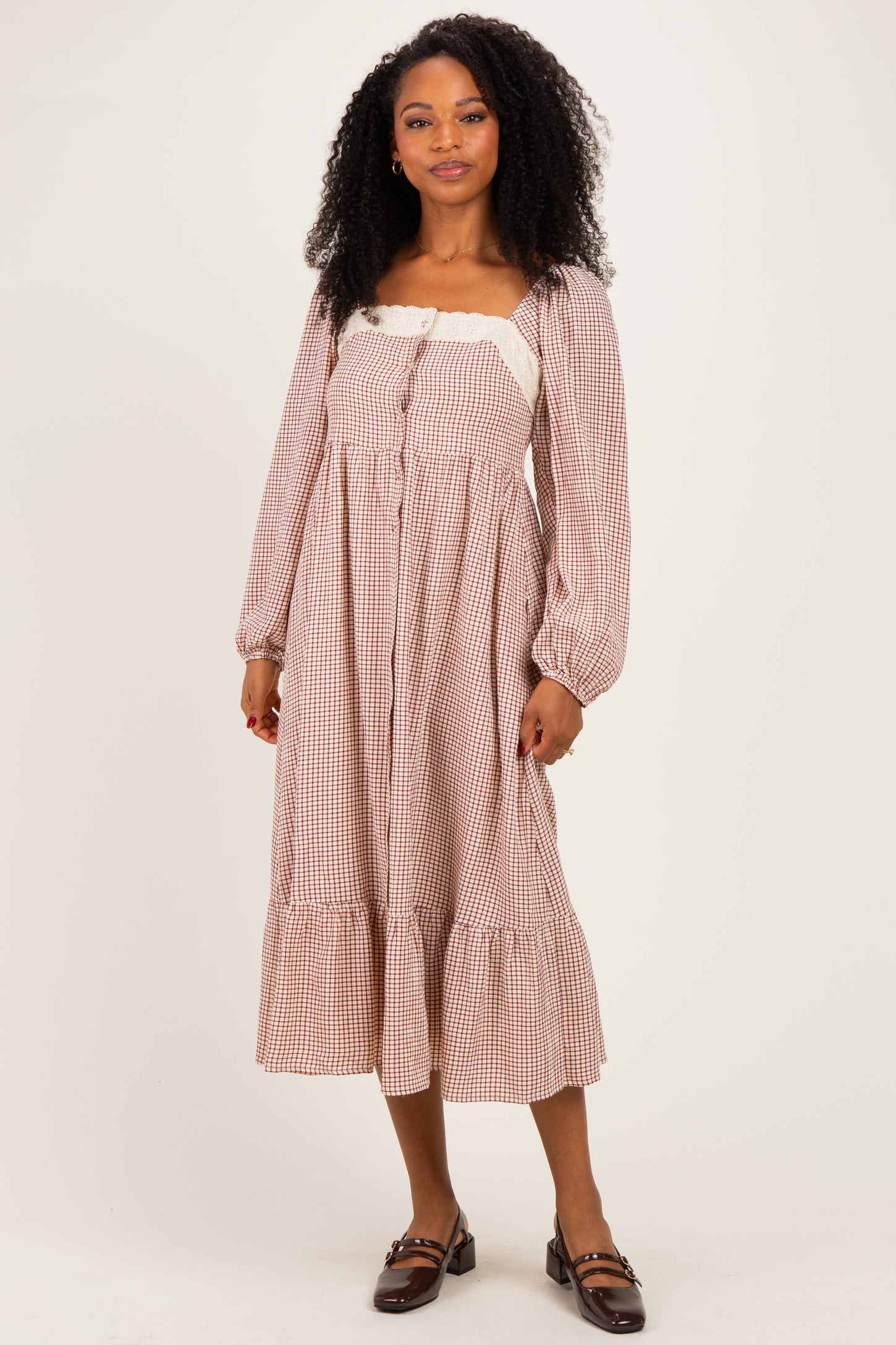 woman wearing a brown and white gingham midi dress with long sleeves and ruffle hem