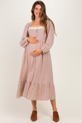 woman wearing a brown and cream checkered maternity dress with puff sleeves and a tiered skirt, holding her baby bump