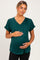 woman wearing a dark green v-neck maternity top with rolled sleeves and holding her baby bump