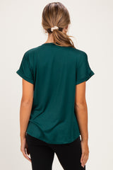 woman wearing a dark green short sleeve maternity top, view from the back with rolled sleeves