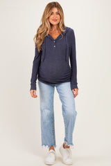 woman wearing a navy blue maternity hoodie with a button detail and distressed light wash jeans, showing her baby bump